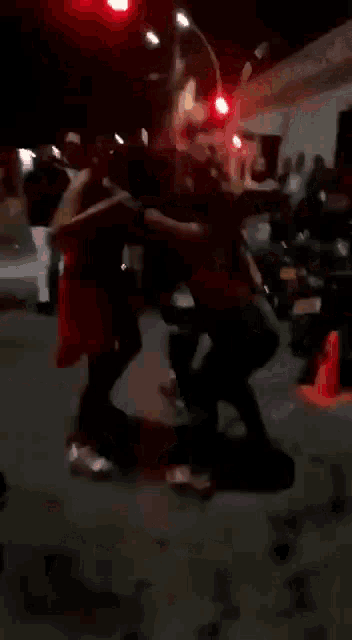 a group of people are dancing in a street at night .