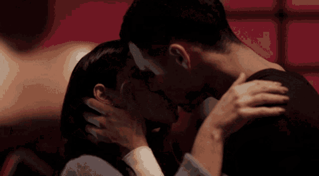 a man and a woman are kissing in the dark
