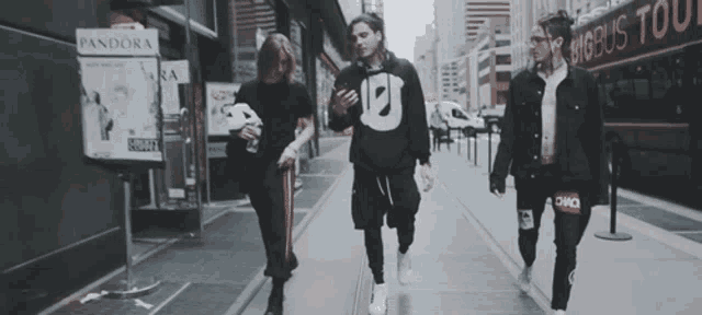 a group of people are walking down a sidewalk in front of a pandora sign