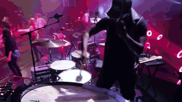 a man in a hat is playing drums in front of a crowd