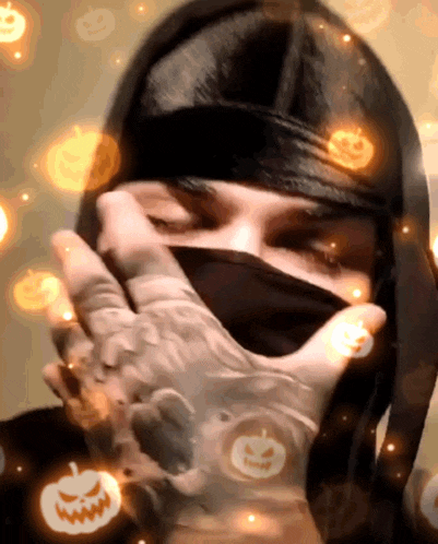a person covering their face with their hand with pumpkins floating around them