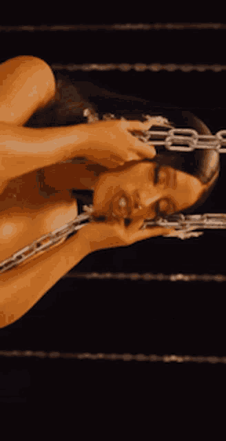a naked woman is chained to a rope in a boxing ring