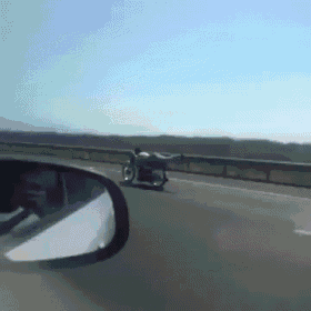 a person is riding a motorcycle down a highway in front of a car .