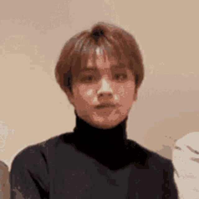 a close up of a young man wearing a black turtleneck sweater .