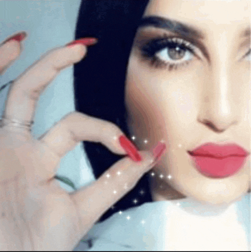 a close up of a woman 's face with red lipstick and long nails