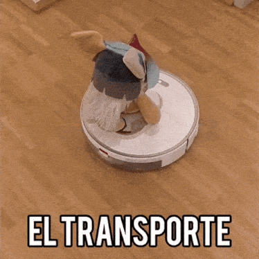 a stuffed animal is sitting on top of a robotic vacuum cleaner that says el transporte on the bottom