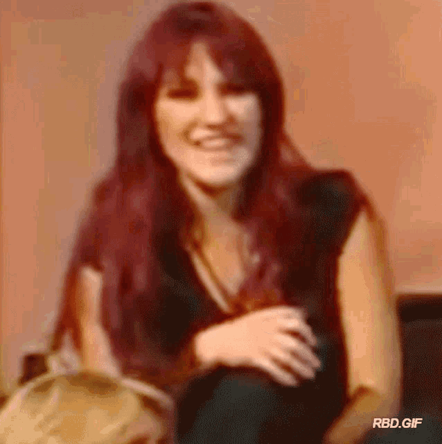 a woman with red hair is smiling and sitting on a couch .