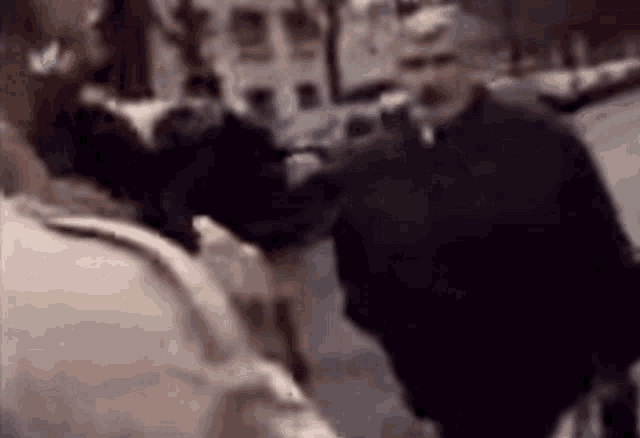 a blurry picture of two men standing next to each other on a sidewalk .