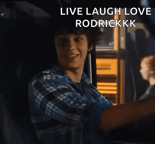 a young man in a plaid shirt is sitting in front of a yellow school bus with the words live laugh love rodrickkkk