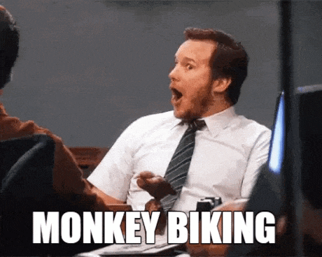 a man in a suit and tie is sitting in front of a computer with his mouth open and the words monkey biking above him
