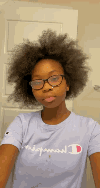 a girl wearing glasses and a champion t-shirt takes a selfie