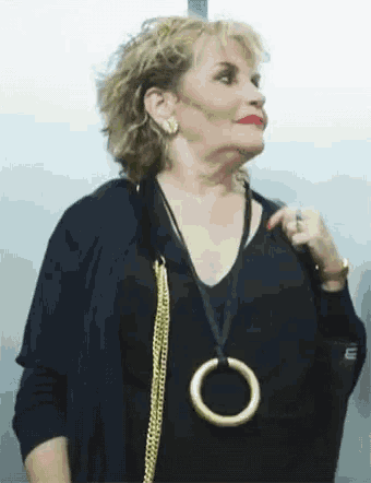 a woman wearing a black shirt and a gold necklace with a circle on it