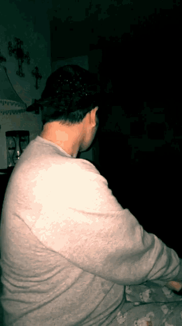 a man in a gray shirt is sitting in a dark room