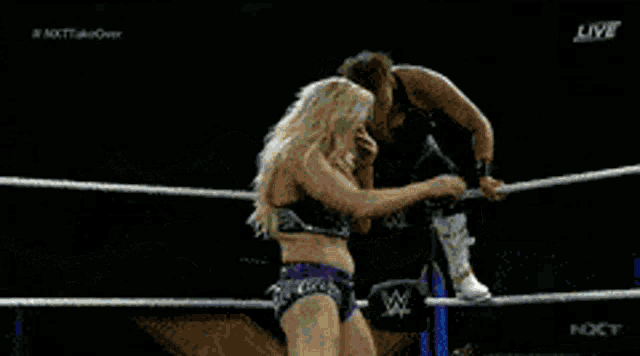 two women are wrestling in a ring with a sign that says " your wife " in the background