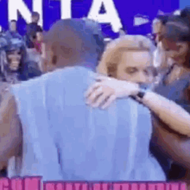 a man and woman are hugging each other in front of a crowd .