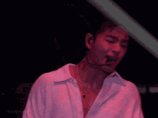 a man wearing a white shirt is singing into a microphone .