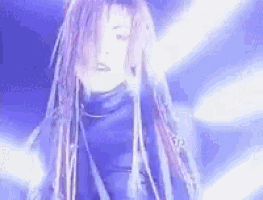 a woman with long dreadlocks is standing in front of a blue light