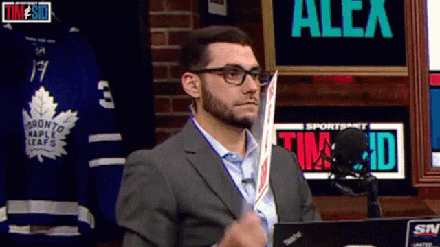 a man in a suit is holding a hockey stick in front of a sportsnet sign