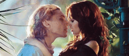 a man and a woman are kissing in front of a tree .