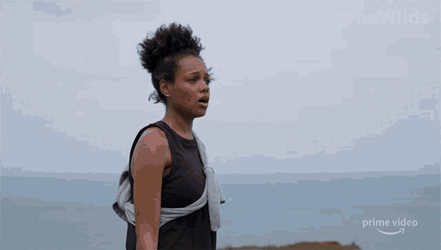 a woman is standing on a cliff overlooking the ocean with #thewilds written on the bottom right