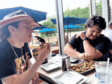 two men are sitting at a table with a napkin that says inno on it