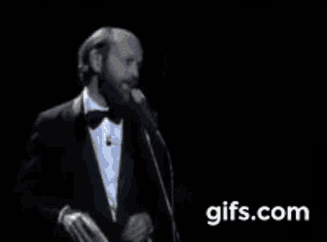 a man in a tuxedo is standing in front of a microphone .