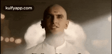 a bald man with a tattoo on his forehead is standing in front of a smokey background .