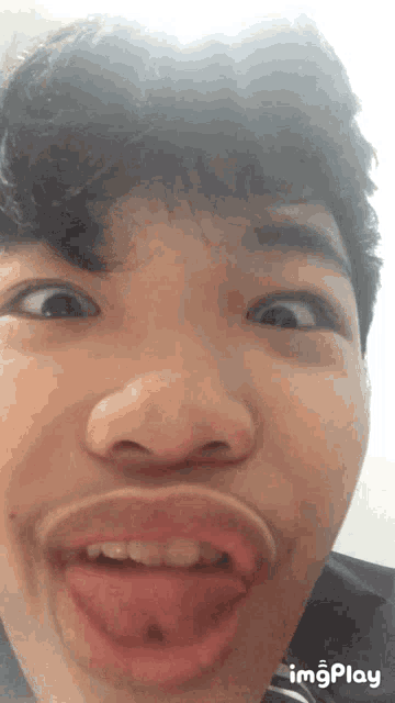 a close up of a young man making a funny face with his tongue hanging out and the words imgplay below him