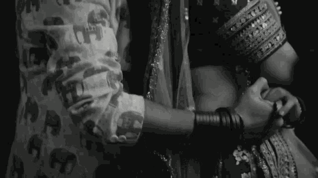 a black and white photo of a man holding a woman 's hand .