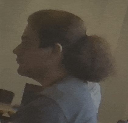 a woman with a ponytail is sitting at a table with a laptop .