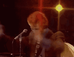 a man in a suit and tie is singing into a microphone with his hands in the air .