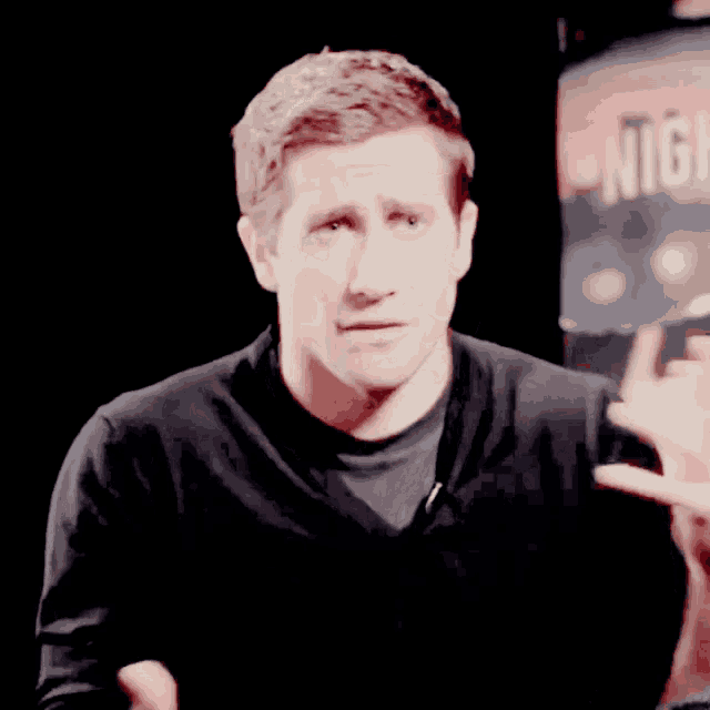 a man in a black shirt stands in front of a poster that says night