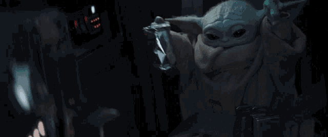 a baby yoda is holding a bag of food in his hand