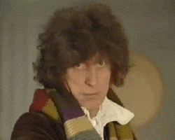 a man with curly hair is wearing a scarf around his neck and looking at the camera .