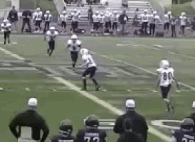 a group of football players are playing on a field with a referee watching .