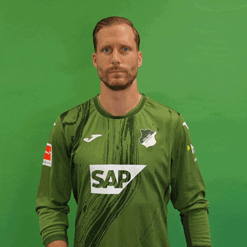 a man wearing a green jersey and gloves with the letter g on the glove