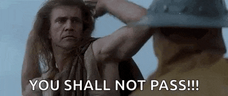 a man with long hair is standing next to a man with a helmet and says `` you shall not pass ! ''