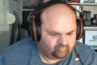 a bald man with a beard wearing headphones and a blue shirt