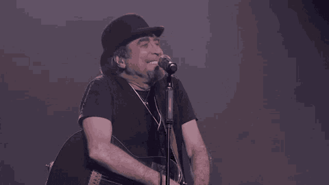 a man is playing a guitar and singing into a microphone on a stage .