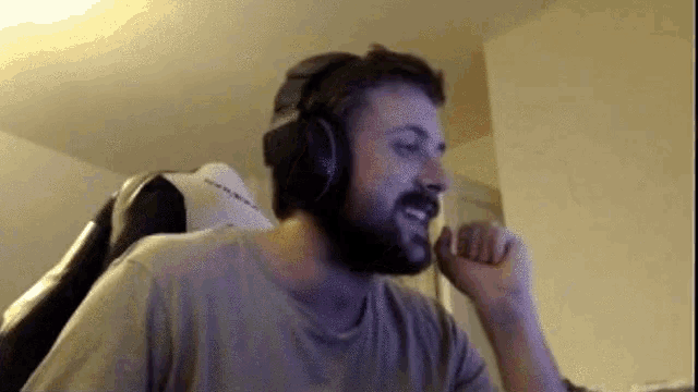 a man with a beard is wearing headphones and sitting in a chair .