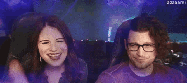 a man and a woman are sitting next to each other in a dark room with azaaami written on the bottom right