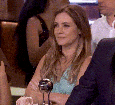 a woman in a blue dress sits at a table with a glass of wine