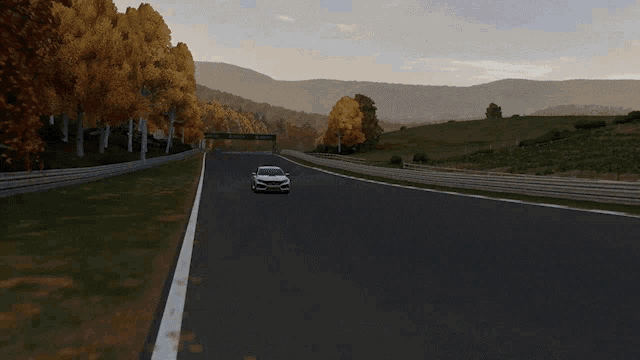 a white car is driving on a race track with windmills in the background