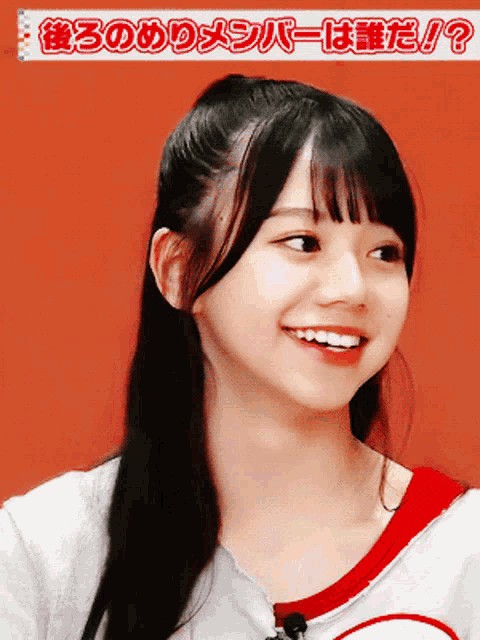 a girl is smiling in front of a red background with japanese writing
