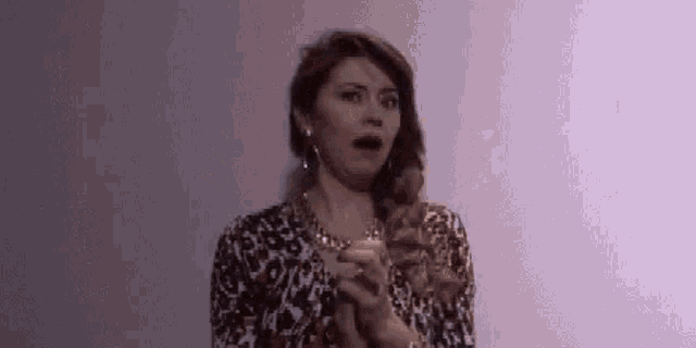 a woman in a leopard print dress is holding a candle and making a funny face .