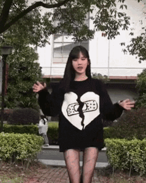 a woman wearing a black sweater with a broken heart on it .