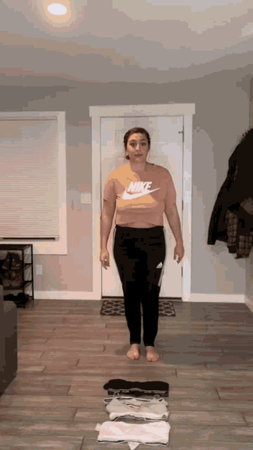 a woman wearing a pink nike t-shirt and black pants