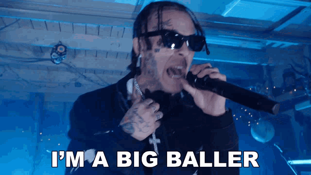 a man singing into a microphone with the words i 'm a big baller behind him