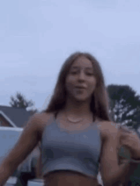 a young woman in a crop top is standing in front of a car .