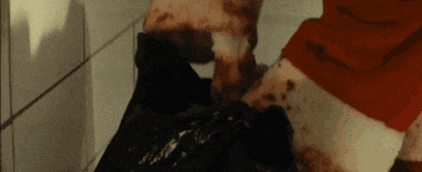 a person in a red shirt is standing in a bathroom with blood on their feet .
